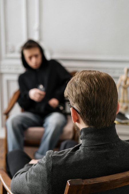 A blurred image of a young man talking to someone with his back to the camera
